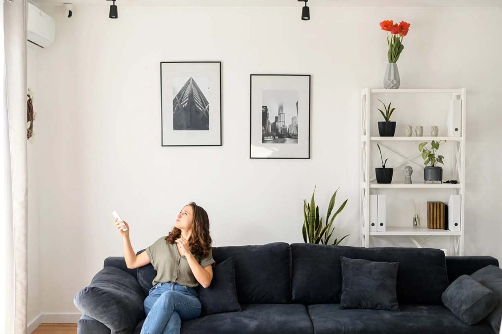 Lady Pressing the Power Button on a Wall-Mounted Ac Unit